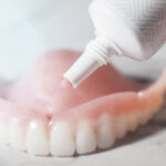 image of denture adhesive being applied to a denture.