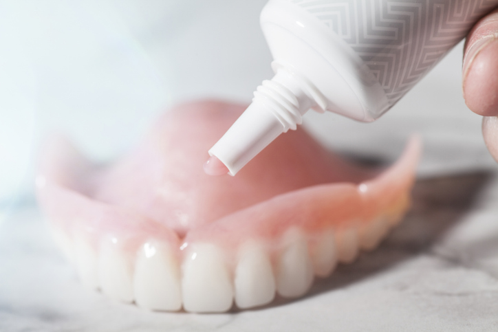 image of denture adhesive being applied to a denture.